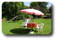 Zicht op tuin met ligstoel, parasol en schommel